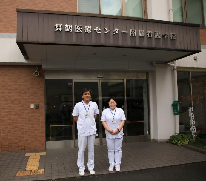 舞鶴医療センター附属看護学校の玄関に立つ竹ノ内さん、山口さん