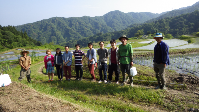 写真:上世谷地区の棚田で農家の方から話を聞く学生