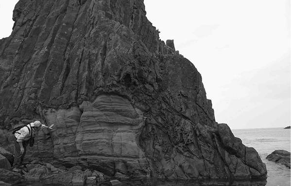 竹野港西方の露頭。水平な層理が見える部分は砂岩層、垂直な節理の部分は安山岩