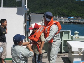 平安丸に乗船してまず、救命胴衣の着用を船員から指導してもらいました。
