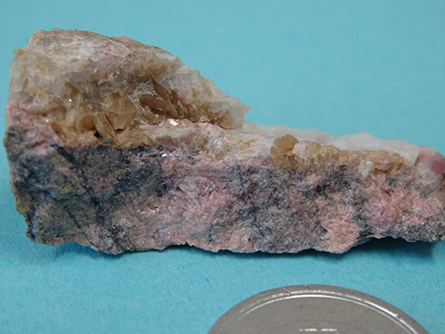 玉岩鉱山のチンゼン斧石（益富地学会館標本）。橙色の結晶群