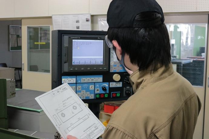 操作盤でNCフライス盤にプラグラムを入力している様子