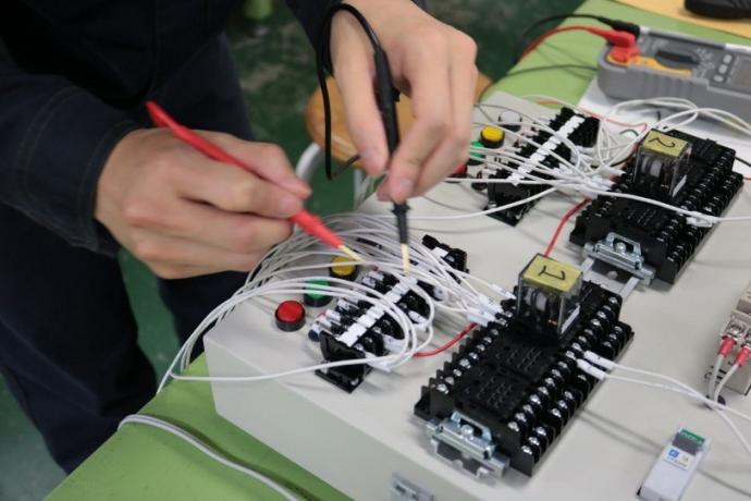 テスターを使って制御盤の配線が短絡していないかを確認している様子