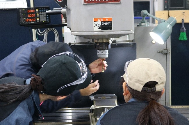 先輩訓練生から刃物の交換の仕方を教わっている様子