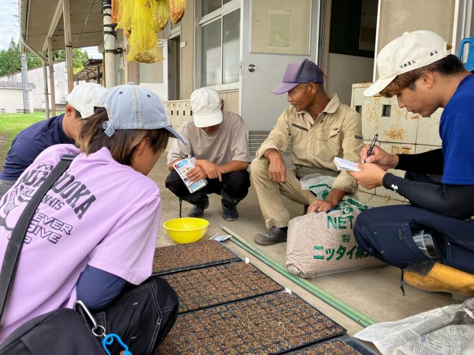 育苗作業の指導を受ける学生の写真