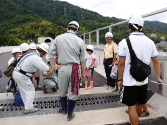 橋の伸縮について説明する道路公社職員