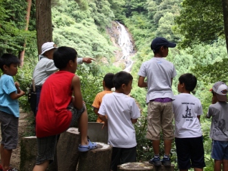 眺望所で滝の説明を聞く男の子たち